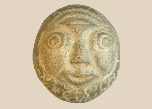 Hand-carved folk art stone face sculpture with expressive eyes and smiling mouth