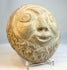 Vintage carved stone face sculpture photographed against neutral background