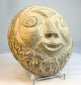 Vintage carved stone face sculpture photographed against neutral background