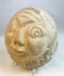 Side profile of carved stone face effigy showing engraved decorative details
