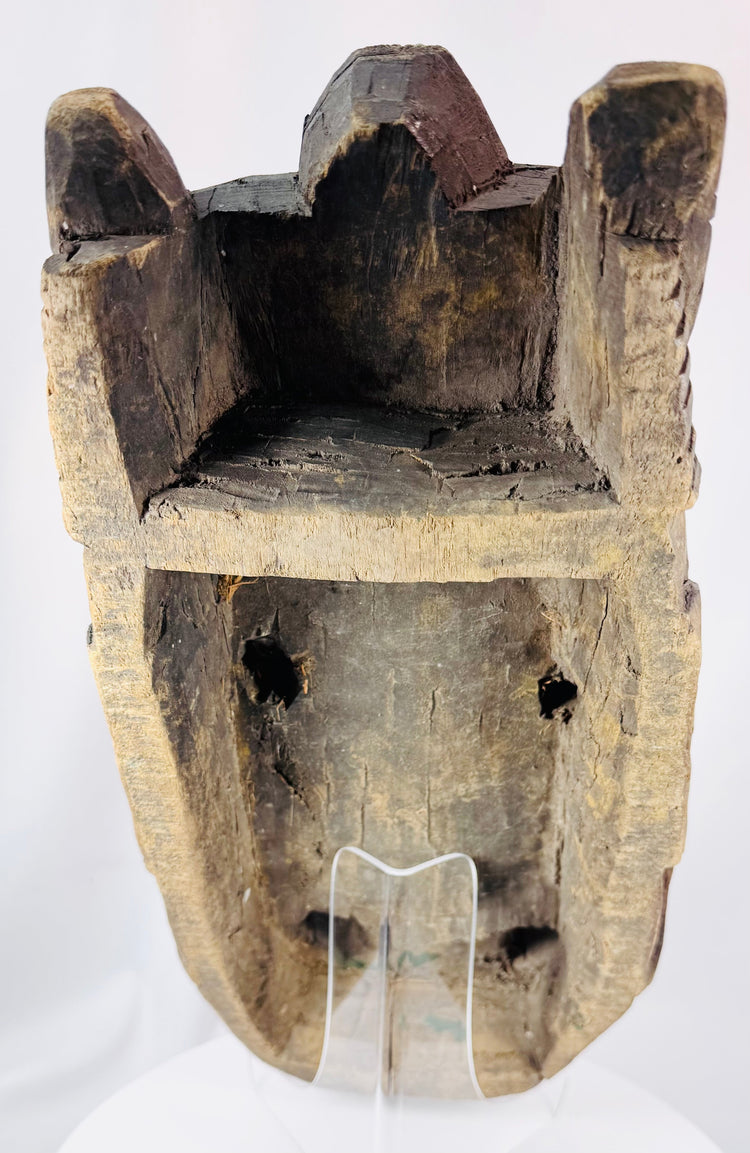 West African ritual mask featuring symbolic facial motifs, recessed eyes, and carved headdress crest.