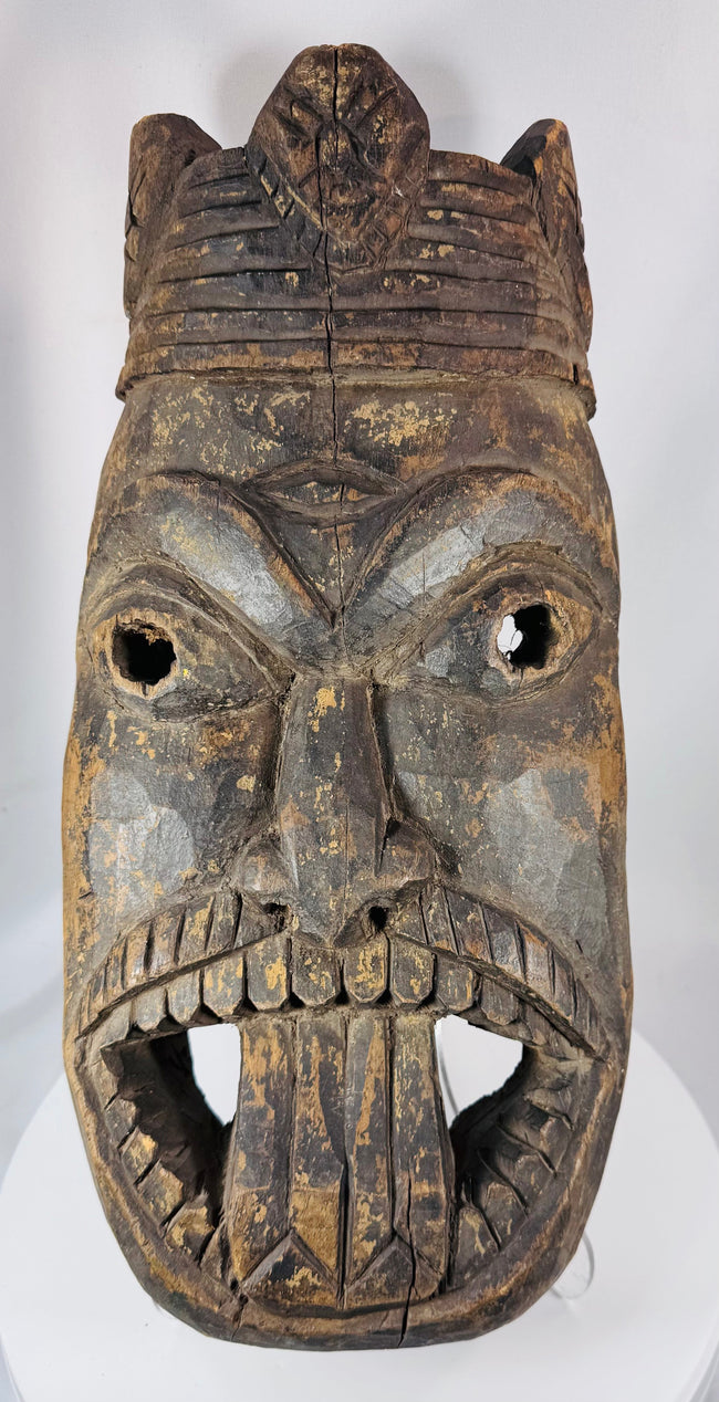 Traditional African ceremonial mask with elongated nose, projecting tongue motif, and carved headdress.