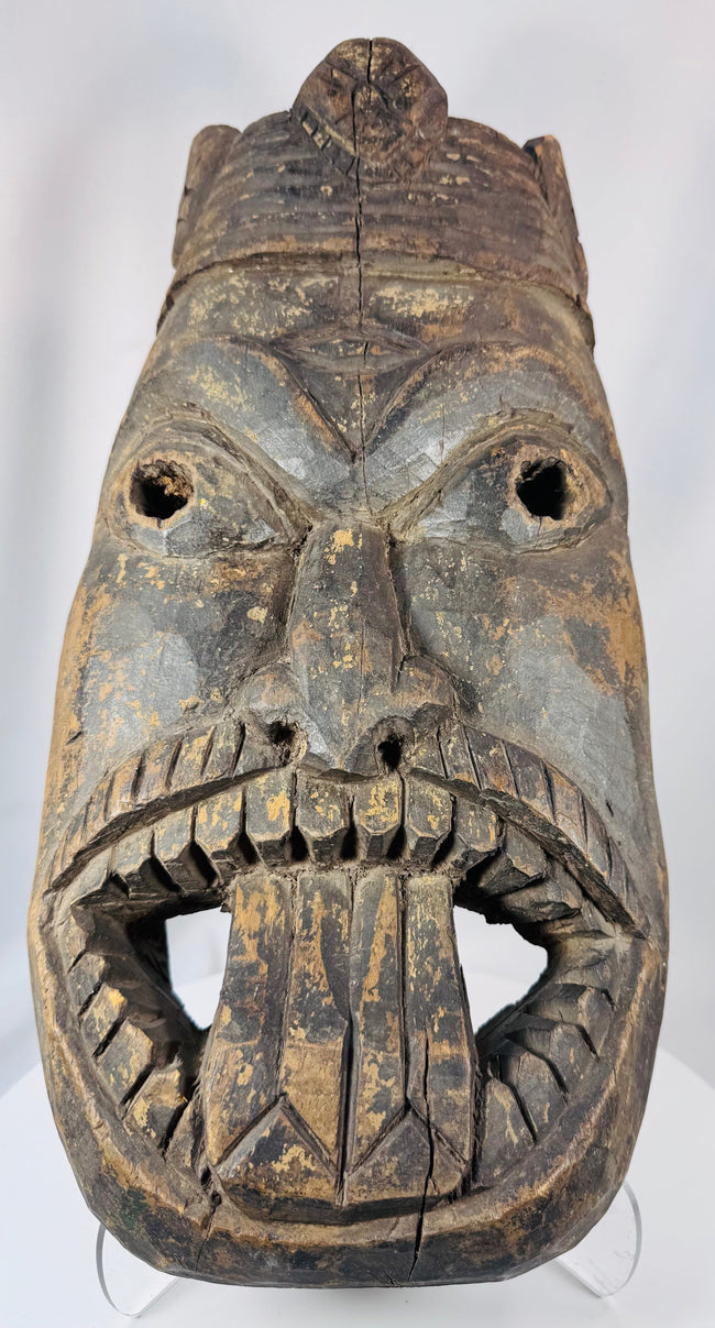 Hand-carved West African wooden ritual mask featuring recessed eyes, carved teeth, and aged patina.
