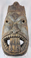 Hand-carved West African wooden ritual mask featuring recessed eyes, carved teeth, and aged patina.