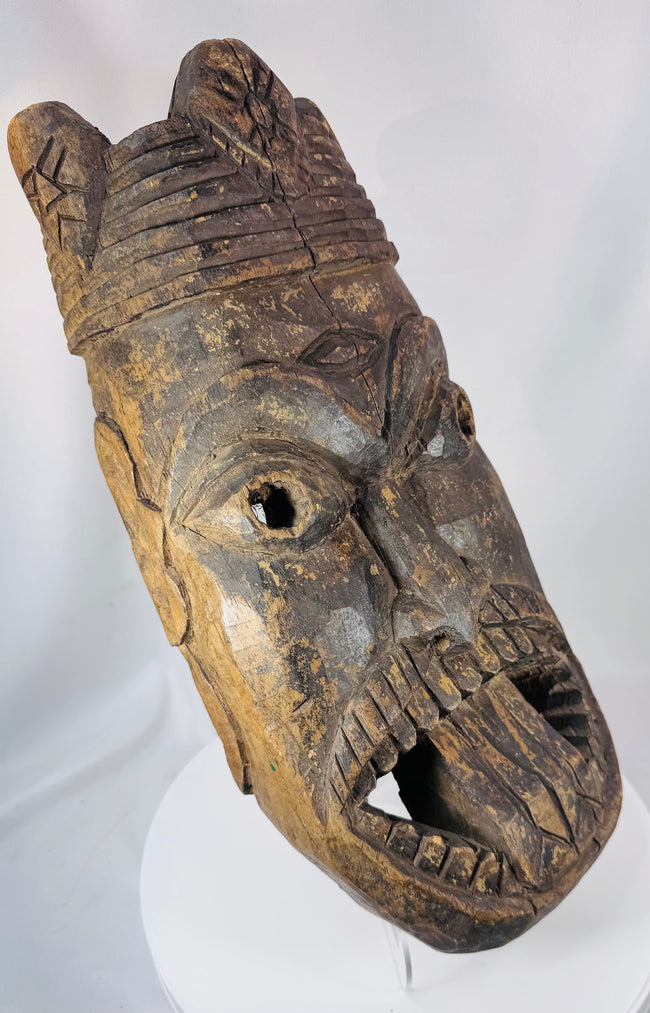 Antique tribal mask from West Africa with stylized facial features and deeply hollowed hand-carved interior.