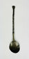 Overhead back view of ancient bronze spoon showing reverse side of bowl, twisted handle, and aged green patina from antiquity.
