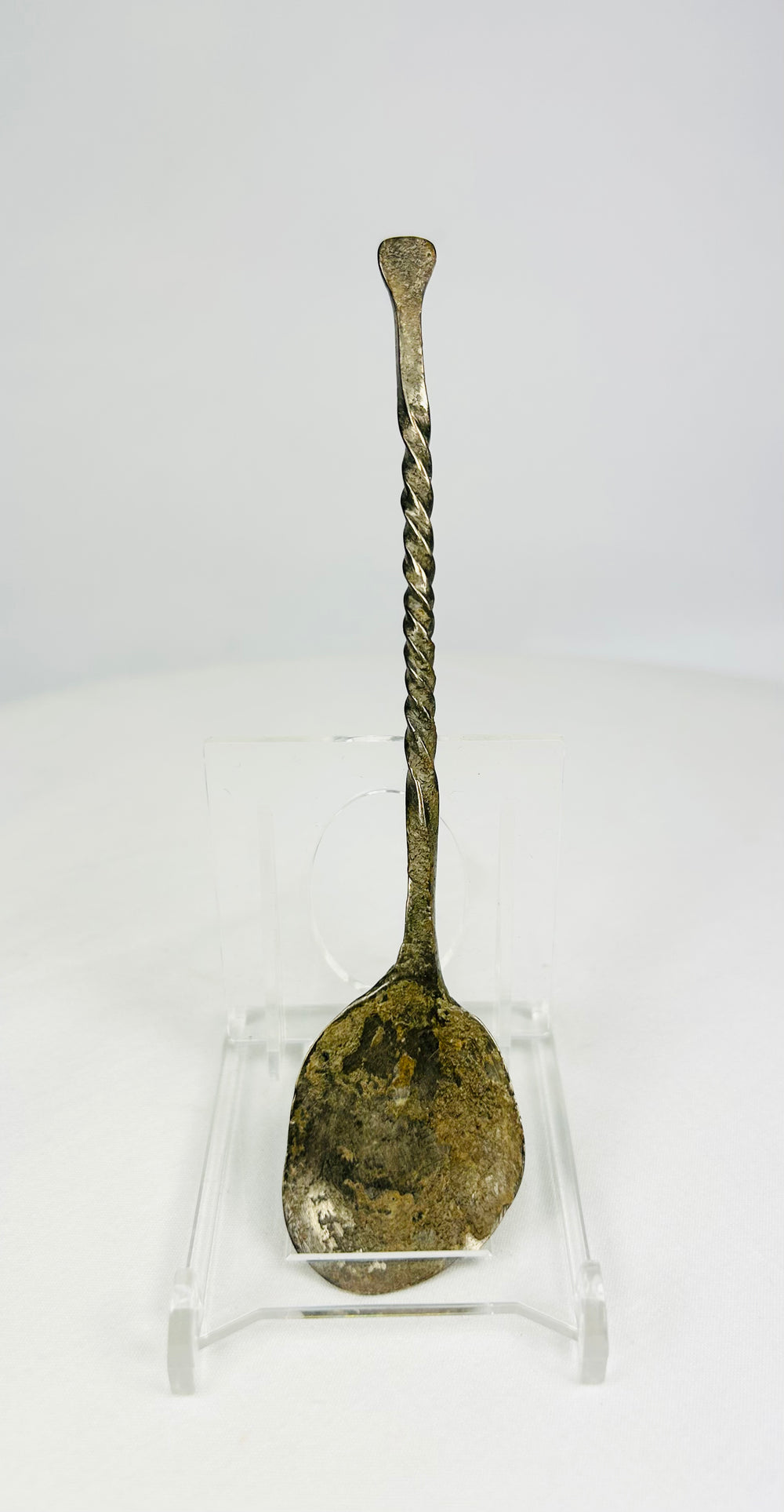 Hand-forged bronze spoon with twisted handle on white background, circa 2nd century AD