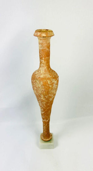 Ancient Hasmonean terracotta bottle from Judea, circa 300–100 BCE. Slender neck with narrow mouth, elongated rounded body, and naturally aged patina. Mounted on a later marble base for display. Functional and elegant vessel used for oils, perfumes, or sacred substances, reflecting daily life and material culture of ancient Judea.