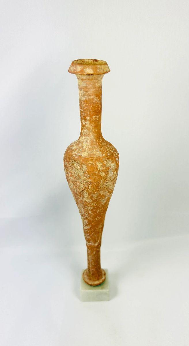 Ancient Hasmonean terracotta bottle from Judea, circa 300–100 BCE. Slender neck with narrow mouth, elongated rounded body, and naturally aged patina. Mounted on a later marble base for display. Functional and elegant vessel used for oils, perfumes, or sacred substances, reflecting daily life and material culture of ancient Judea.