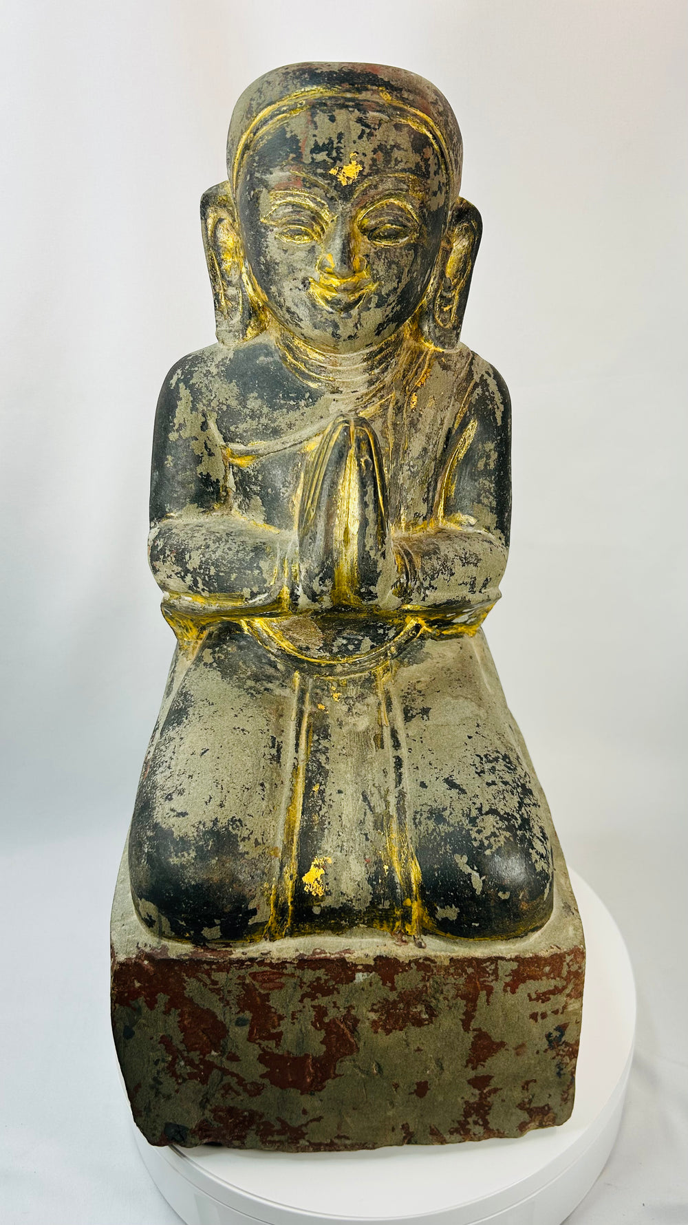 Burmese Buddhist kneeling attendant sculpture with hands pressed together in prayer.