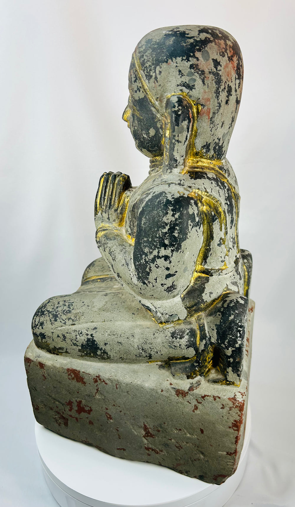 Burmese temple sculpture of a kneeling worshipper with elongated ears and serene expression.