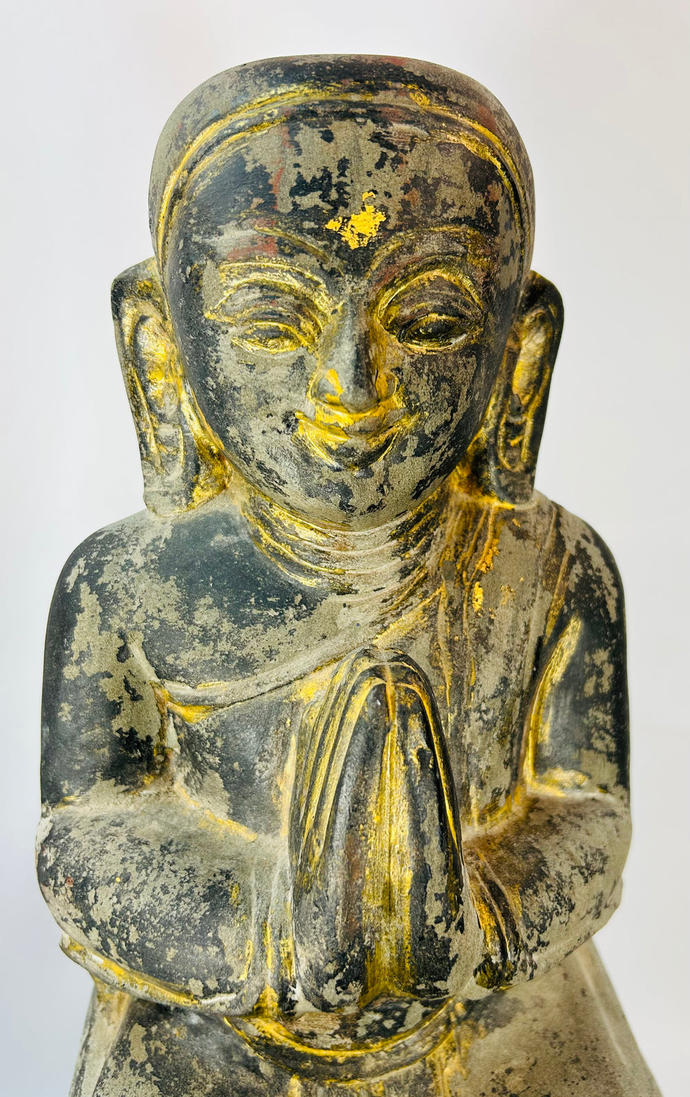 Historic Burmese Buddhist temple sculpture of a kneeling devotee with aged gilding.