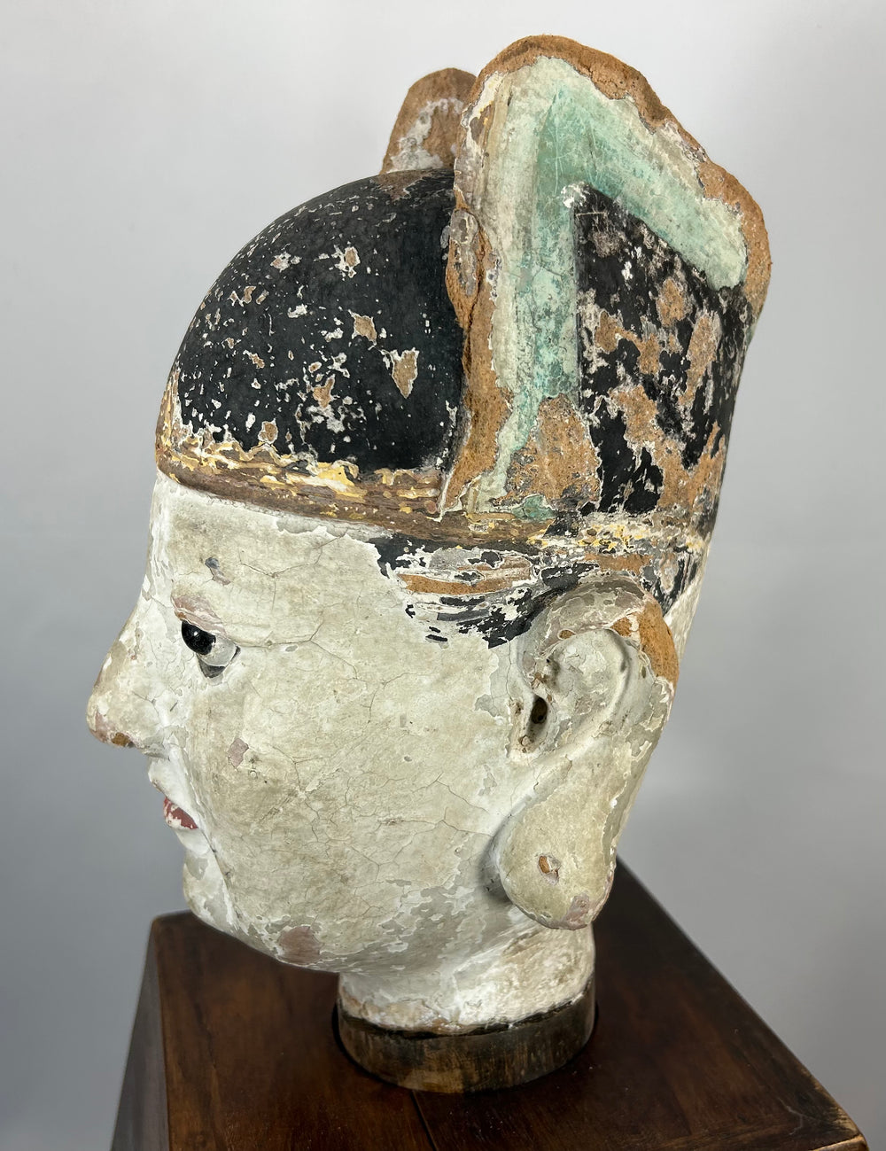 Antique Chinese terracotta official figure with elongated ears and painted features.