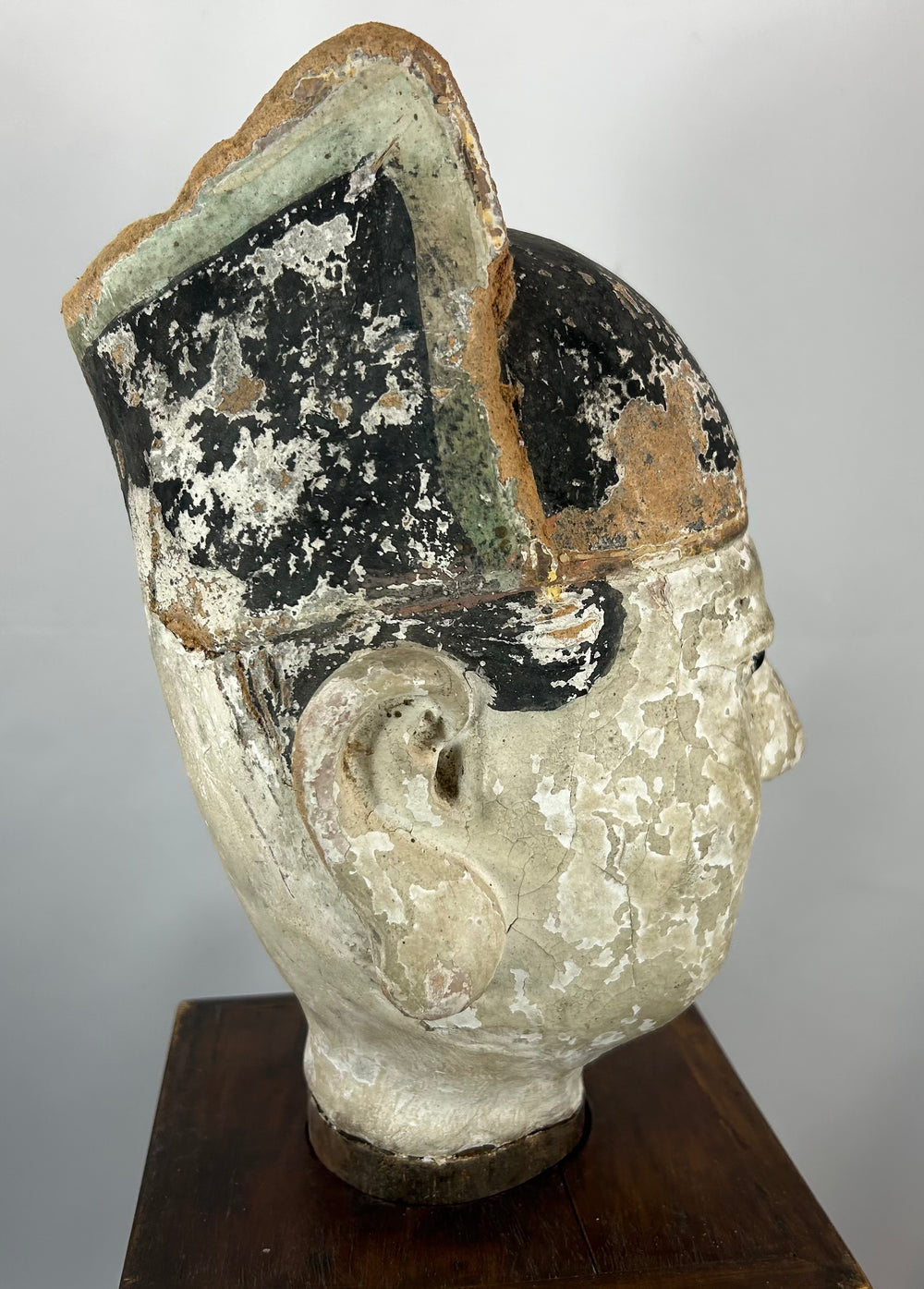 Chinese temple sculpture bust with black lacquer hat and pale mineral slip face.