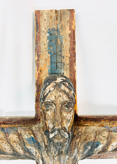 Spanish Colonial Christ on cross sculpture with aged surface and polychrome traces.