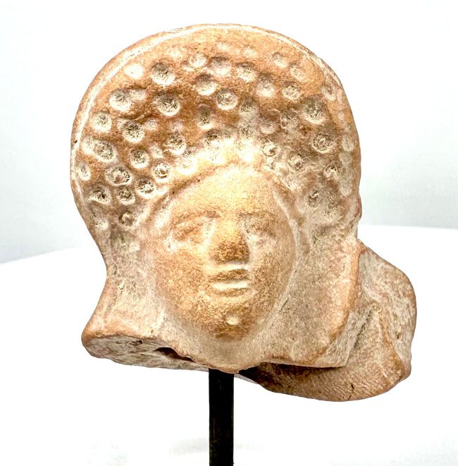 Ancient Roman female protome with a high rounded coiffure decorated with circular curls, softly modelled face, and reddish-buff terracotta surface.