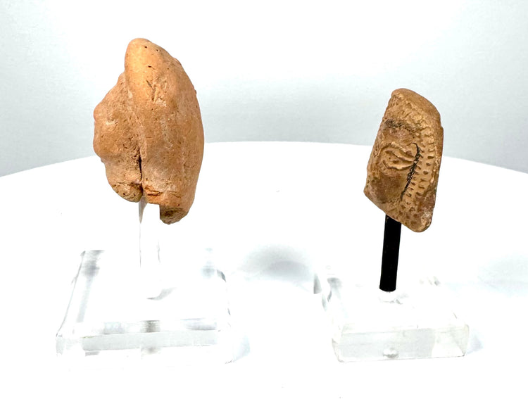 Ancient Greek female terracotta head featuring raised ornamental hair detailing, prominent eyes, and a distinctive trapezoidal silhouette.