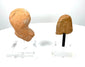 East Greek female protome displaying closely arranged hair impressions, weathered buff-coloured terracotta, and dark deposits within recessed details.