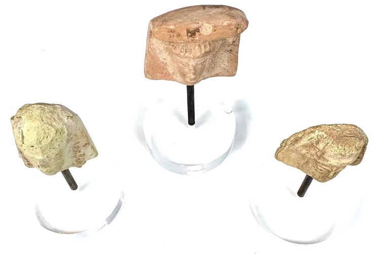 Set of three ancient Mediterranean terracotta female protomai featuring varied sculptural styles, aged ceramic surfaces, and individual museum-style display mounts.