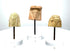 Collection of three ancient Greek female terracotta head fragments with stylized facial features, contrasting earthenware surfaces, and acrylic display stands.