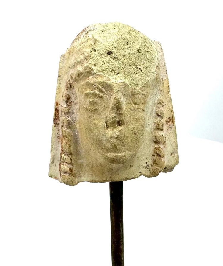 Ancient Greek female terracotta protome featuring a rounded headdress, elongated facial features, and heavily weathered pale cream-coloured clay.