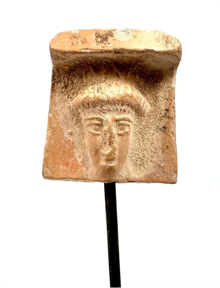 Archaic Greek terracotta female head fragment displaying a broad veil-like covering, softened facial modelling, and natural surface encrustations.