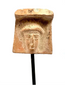 Archaic Greek terracotta female head fragment displaying a broad veil-like covering, softened facial modelling, and natural surface encrustations.