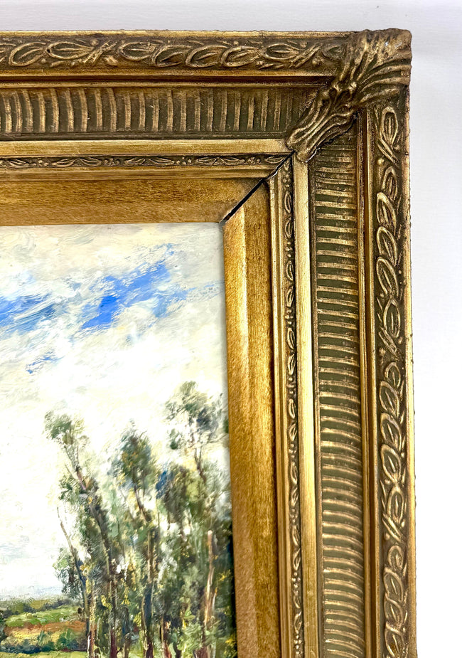 Vintage oil on canvas painting featuring tall riverside trees, rolling green fields, soft white clouds, and an expansive blue sky.