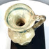 Late Antique Roman glass jug with extensive mineral encrustations, beige surface deposits, and areas of distinctive blue-green patination.