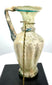Late Roman–Early Byzantine glass jug displaying a wide trumpet-shaped mouth, thickened rounded rim, and weathered translucent glass.