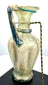 Ancient Roman glass pouring vessel with a gracefully curved handle, applied glass collar, and richly textured archaeological surface deposits.