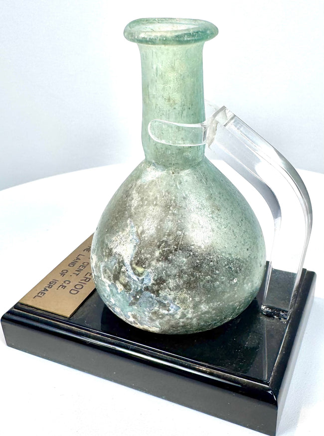 Ancient Roman unguentarium featuring a circular mouth, folded glass lip, and mineral accretions preserved around the interior opening.