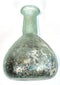 Ancient Roman glass vessel displaying concentrated mineral encrustations, dark earthy deposits, and iridescent weathering across its spherical body.