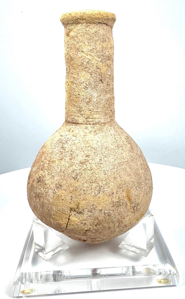 Roman Imperial stone perfume vessel with a spherical body, narrow neck, and weathered buff-coloured surface, catalogued as volcanic tuff.