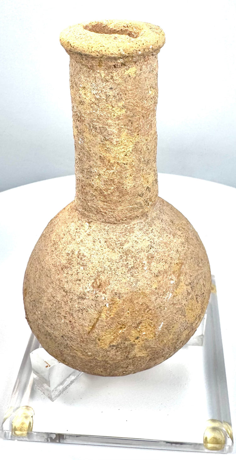 Roman-period carved stone vessel exhibiting extensive mineral deposits, surface abrasions, and natural irregularities across its bulbous body.
