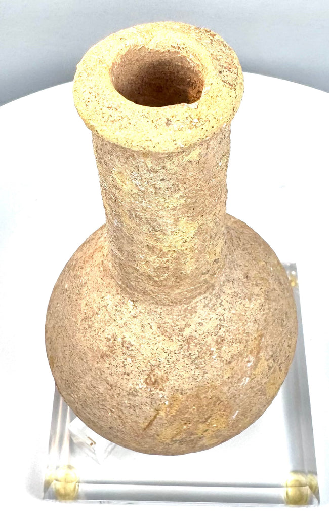 Ancient Roman Imperial unguentarium with a long cylindrical neck, pronounced rounded shoulders, and coarse granular stone texture.