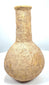 Roman Imperial perfume container with a nearly spherical body, pale buff-coloured stone surface, and scattered earthy encrustations.
