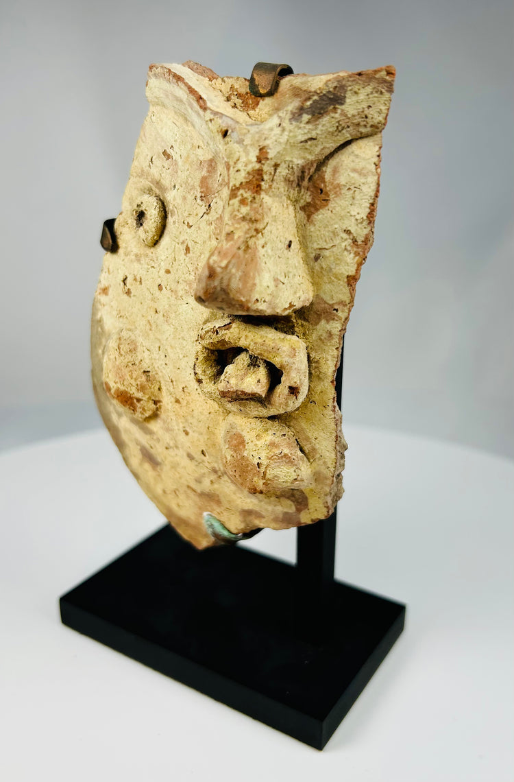 Ancient theatrical mask fragment in terracotta depicting stylized facial features from Greco-Roman dramatic tradition.