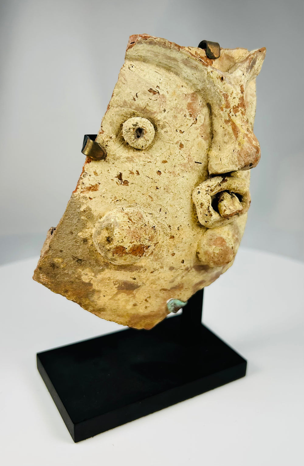Archaeological terracotta fragment of a Greco-Roman theatrical mask mounted on modern display stand.