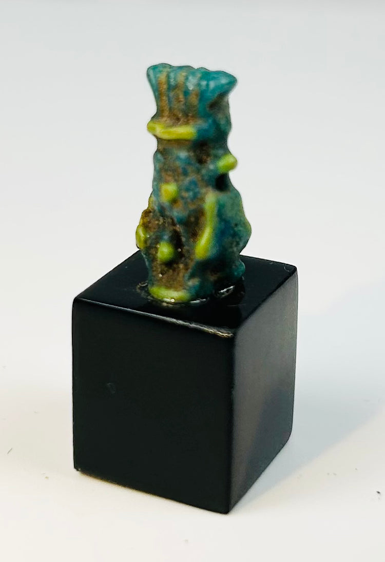 Ancient Egyptian protective charm depicting Bes with stylized facial features.