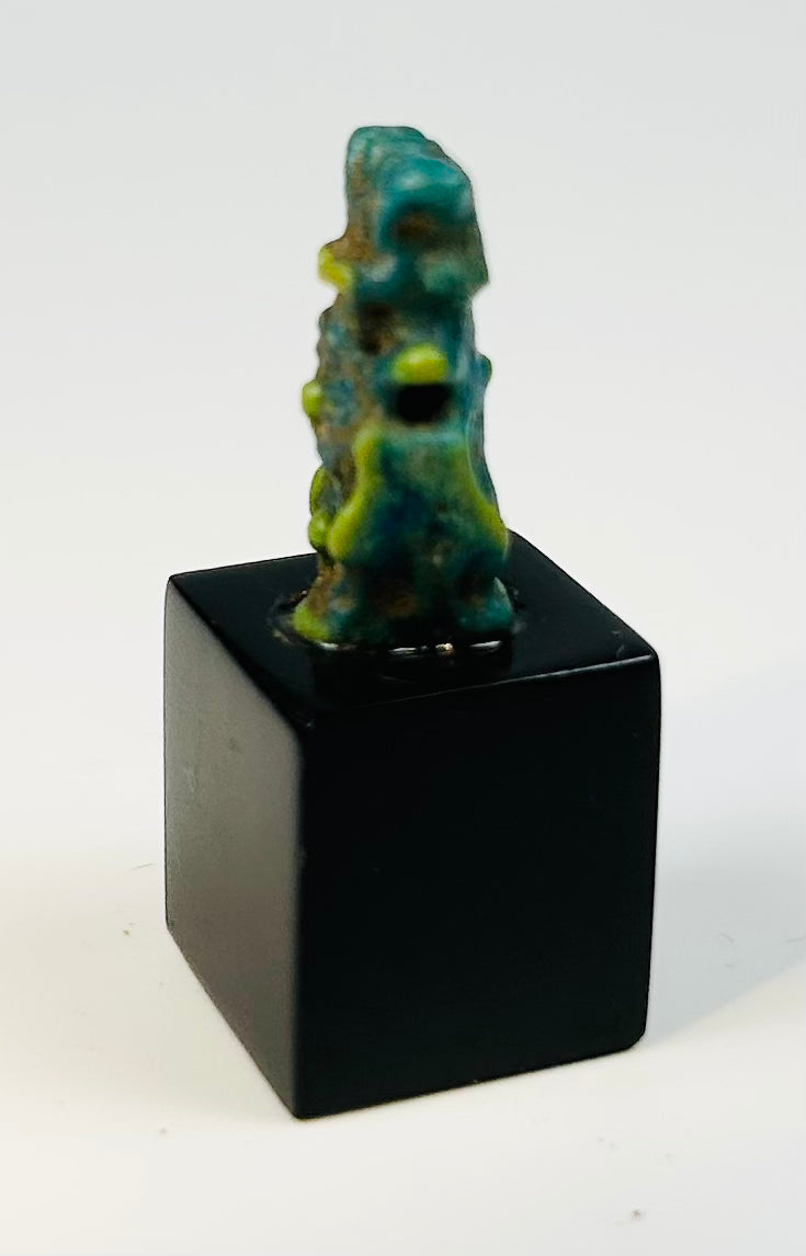 Blue-green faience Bes amulet from ancient Egypt with archaeological patina.