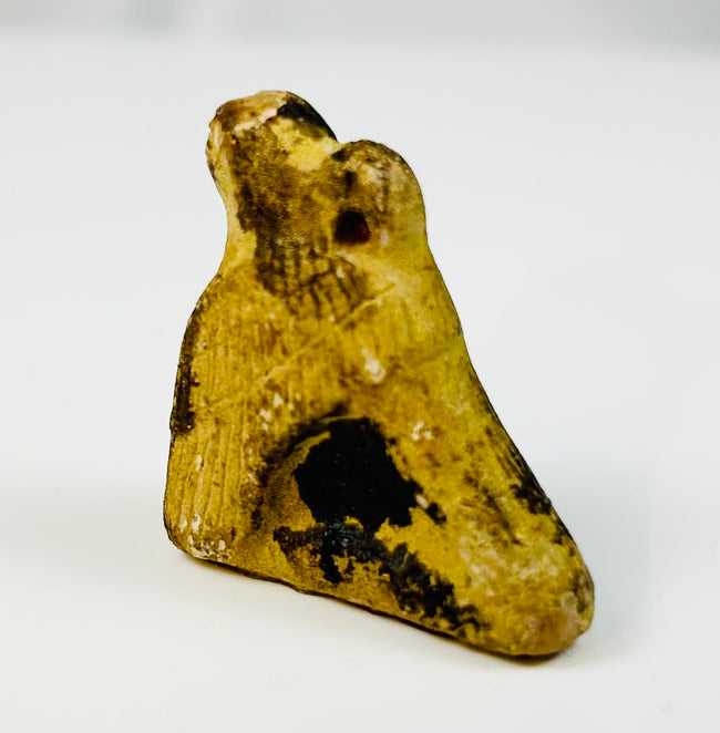 Carved stone falcon amulet from ancient Egypt mounted on display stand.