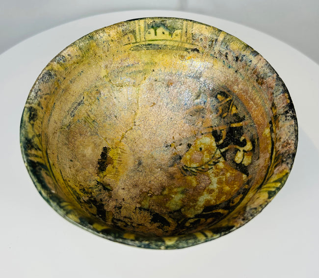 Medieval Islamic pottery bowl with yellow green glaze and black painted details