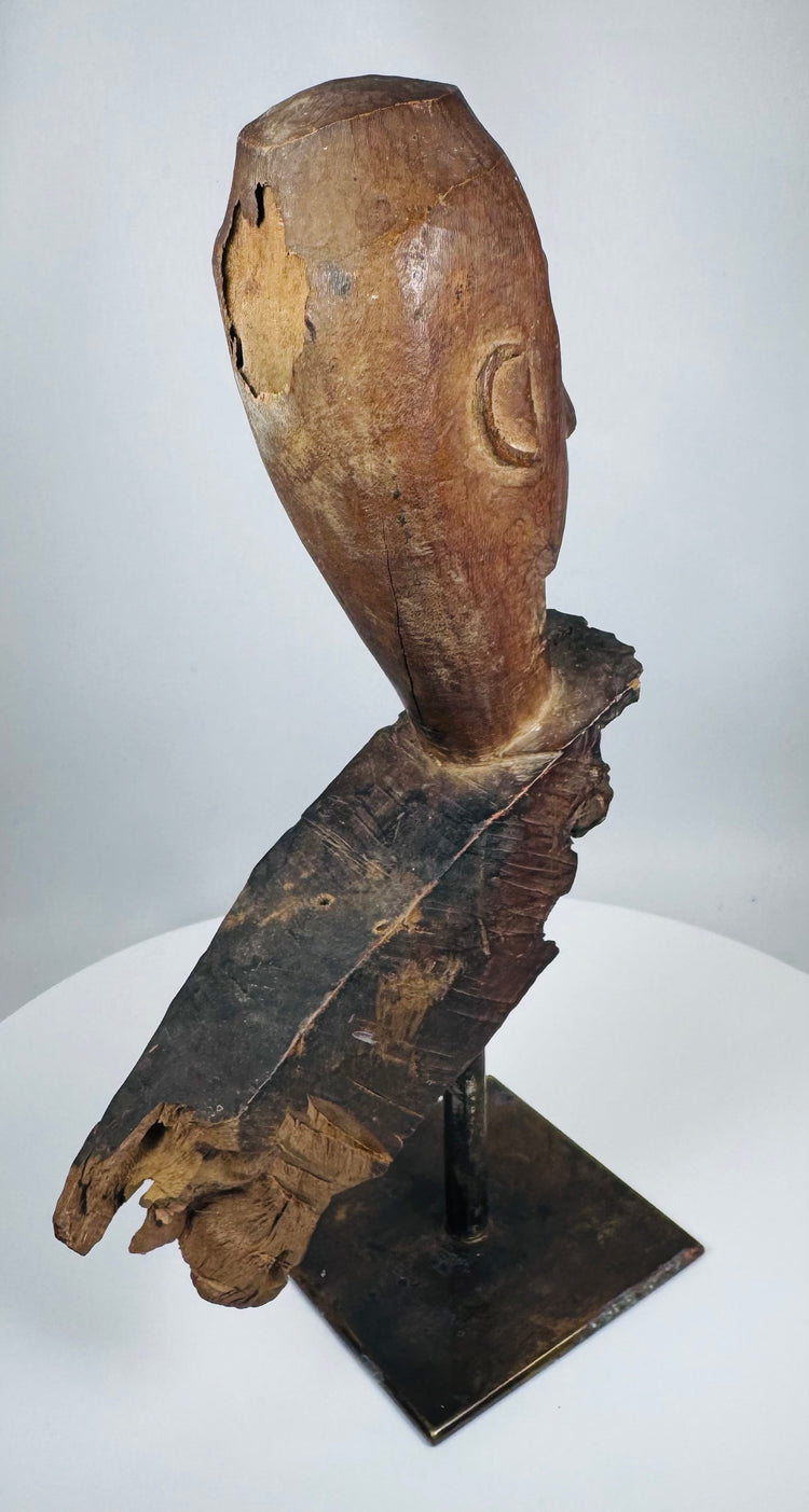 Southeast Asian ritual wood carving fragment featuring expressive almond-shaped eyes and angular nose
