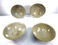 Four Song Dynasty Chinese ceramic bowls featuring pale green celadon glaze, incised floral decorations, and marine encrustations from centuries of underwater submersion.