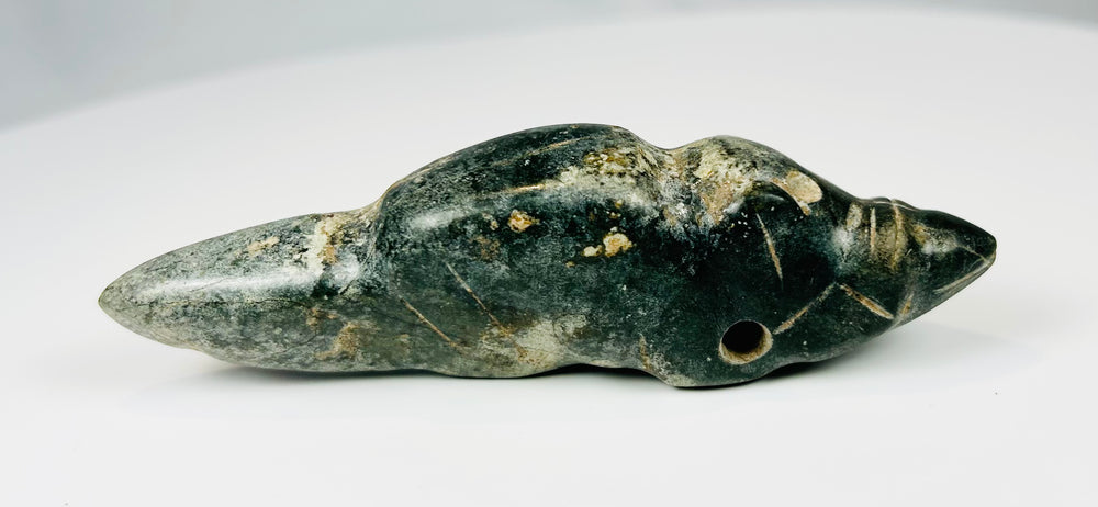 Mesoamerican greenstone pendant featuring reclining animal form and natural patina