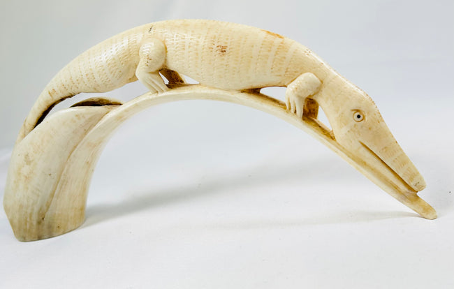 Detailed view of an African hippopotamus tooth carving depicting a crocodile motif, handcrafted early 20th-century ivory artwork displayed on a white background.
