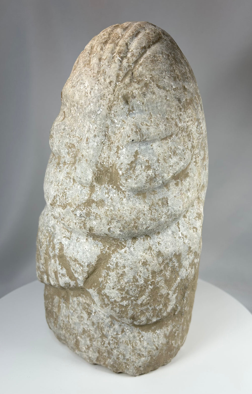 Ancient limestone anthropomorphic sculpture with minimal facial detail and weathering