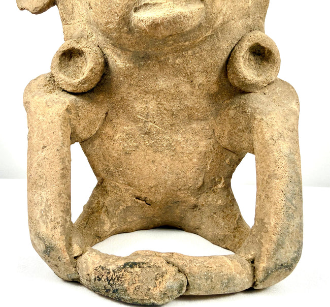 Ancient Mesoamerican terracotta figure with distinctive headpiece projections, sculpted facial details, and visible surface abrasions.