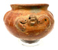 Ancient American terracotta ceramic vessel featuring a rounded profile, ornamental relief details, scattered surface abrasions, and darker areas of patination.
